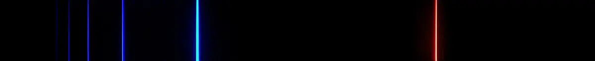 A photograph of hydrogen's visible emission spectrum: thin bright lines on a black background. From right to left, a strong red line, a blue-green line, a fainter blue line, then violet lines that get fainter and closer together.